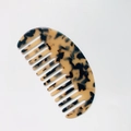 Detail eines breitzinkigen Azetat-Kamms mit Schildpatt-Muster und halbrunder Form - Helles Leopardenmuster