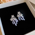 Detailopname van zirkoonbloem- en lila emaille strikoorbellen in een geschenkdoosje. - Zilveren naald / Paars diamant strik bloem cluster stijl (43#)