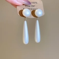 Dettaglio di orecchini pendenti con perle placcati oro 18k tenuti in mano - Bianco Perlato
