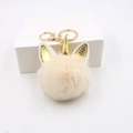 Detalle de llavero de unicornio de peluche con pompón beige y cuerno dorado brillante - Blanco Roto