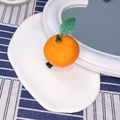Detailed view of realistic orange fruit hair clip with green leaf on a white tray - Mandarin