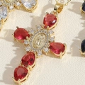 Detail of cross pendant with red teardrop gem and religious figure relief on gold finish - Red