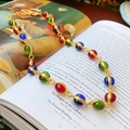 Collier vintage doré avec des perles colorées rouges, vertes et bleues sur un livre - 27# Collier - Collier en alliage doré avec pierres précieuses ovales colorées