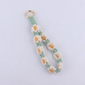 Detail of hand-woven daisy flower keychain with green cotton cord and golden metal ring - Beige