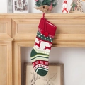 Gestrickter Weihnachtsstrumpf mit Rentier-Muster und roten Bommeln am Kamin - Rentier