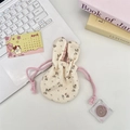 Close-up of floral drawstring bag with rabbit ears and pink checkered lining on a white desk - Beige