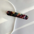 Macro view of rectangular floral hair clip with rhinestones on white ceramic tray - Multicolor