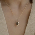 Collana a medaglione ovale dorato con incisione a raggiera su un maglione di maglia - Sole