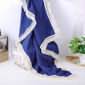 Detail of dark blue muslin baby blanket with white tassel edges on a wicker basket - Navy Blue