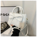 Detail of a white crossbody bag featuring a large decorative bow and elegant PU leather texture - White