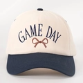 Close-up of GAME DAY embroidery and bow detail on the two-tone cotton baseball cap - Adjustable / Cream/Navy Blue