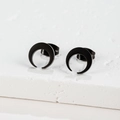 Close-up of matte black crescent moon stud earrings on a textured stone display - Moon / Black