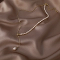 Detailed macro view of baroque pearl necklace laid on luxury champagne silk fabric - Gold/White