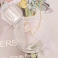Close-up of golden butterfly necklace with transparent resin wings on a glass bottle - White
