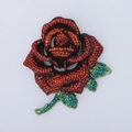 Macro detail of luxury crystal rose brooch with red rhinestones and green stem petals - Red