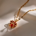 Nahaufnahme der Goldkette mit rotem Herzanhänger und einer zarten Schleifenverzierung - Rot