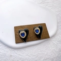 Elegante vergoldete Herzohrringe mit blauem Edelstein und Perlen auf Holzblock - Schwarz