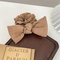 Detail shot of brown satin bow hair scrunchie on a dark wooden tray with prop card - Light Brown Bow