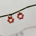 Detalle de pendientes de flores de cristal rojo colgados en una rama de madera rústica - Rojo Multifacético