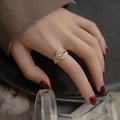 Elegant gold interlocking buckle ring with clear zircons worn by a model on hand - Wraparound Zirconia