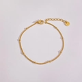 Nahaufnahme von minimalistischem Gold-Edelstahl-Perlenarmband auf hellrosa Grund - Kugelkette
