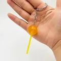 Macro shot of orange translucent lollipop keychain with gold glitter and metal hook - Orange