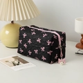 Quilted black cosmetic bag with pink bow print and pearl charm on a cozy desk setup - Square / Black Pink