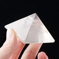 Hand holding a transparent natural white crystal pyramid with a polished clear finish - 7.5cm