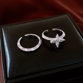 Detalle de set de anillos de flor plateados con circonitas sobre cuero negro y seda roja - Juego de Dos Piezas de Flores Plateadas