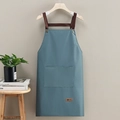 Waterproof teal apron with brown straps and large front pocket on wooden hanger - Leather Label Blue