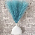Artificial blue pampas grass bouquet in a white vase against vintage newspaper background - Tiffany Blue