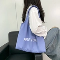 Detailweergave van lavendel canvas draagtas met witte AREYOU letters erop - Lichtblauw