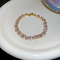 Detail of gold-plated bracelet with rectangular zircon clusters in a ceramic dish - Bracelet & Bangle 3-Piece Set / Gold