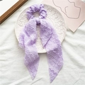 Elegante paarse scrunchie met lange linten en gestructureerde stof op een wit bord - Stijl met streamer / Paars