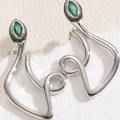 Macro shot of silver snake earrings with marquise green stones on white marble base - XL2607-5 Snake Studs White Gold Plated