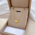 Detailed view of a gold V-shaped heart pendant necklace with zircon in a beige jewelry box - Gold