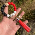 Dettaglio del portachiavi a bracciale in perline di silicone con nappa rossa e oro - Rosso