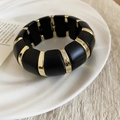 Detailed macro of matte black acrylic beads with polished gold spacers on elastic band - Round Style / Gold-Black