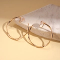 Detail of gold spiral twisted clip-on hoop earrings on white marble background - 6cm / Gold