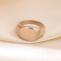Polished rose gold signet ring with a flat round surface on champagne satin background - US 7 / Rose Gold