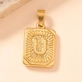 Macro shot of gold square pendant with embossed letter U and radiating textured edges - Letter U