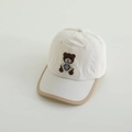 Close-up van teddybeerborduurwerk op een crèmekleurige babyhonkbalpet met kaki bies - 50-54cm / Beige