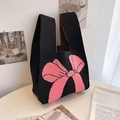 Close-up of a black knitted tote bag featuring a large pink bow on a white desk - Black and Rose Red Bow