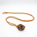Macro detail of natural black stone pendant with handcrafted orange woven mesh and wooden beads - Obsidian