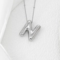 Polished silver balloon letter N pendant necklace on white satin and textured surface - Letter N Pendant