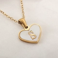 Golden heart necklace with white shell inlay and letter S charm on silk background - Letter S