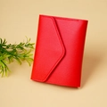 Detail of red faux leather wallet with lychee texture and stitching on cream background - Red