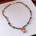 Dettaglio della collana di perline con ciondolo a elefante e cuore in zircone blu - Collana-Marrone-Blu