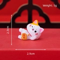 Miniature resin fortune cat figurine lying sideways with golden tablet on red background - Lucky Cat Wealth