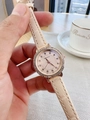 Detailed view of champagne leather strap watch with rhinestone bezel worn on wrist - Apricot